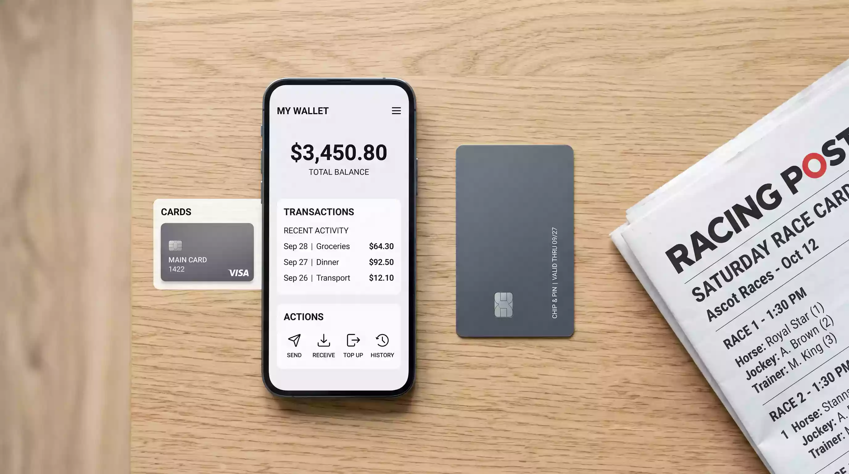 Debit card and smartphone with a PayPal screen placed on a table next to a racing form newspaper